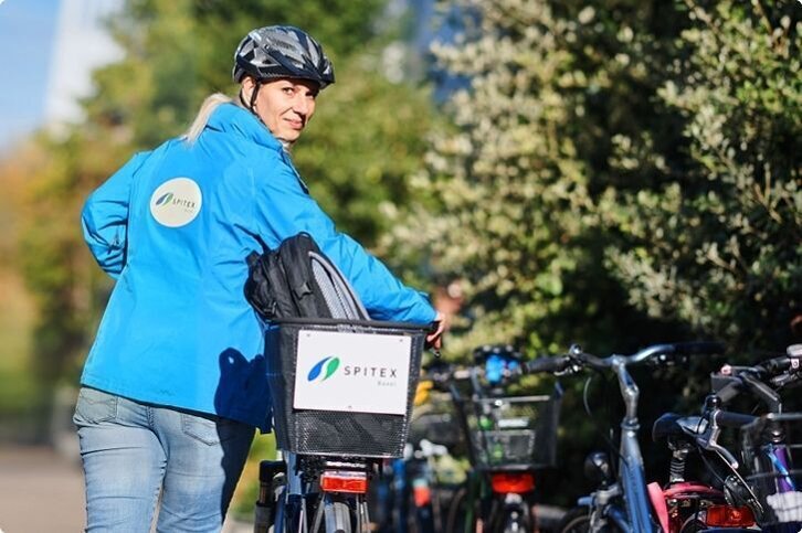 Mit dem Velo unterwegs zum nächsten Einsatz Mitarbeiterin von SPITEX BASEL mit Velo